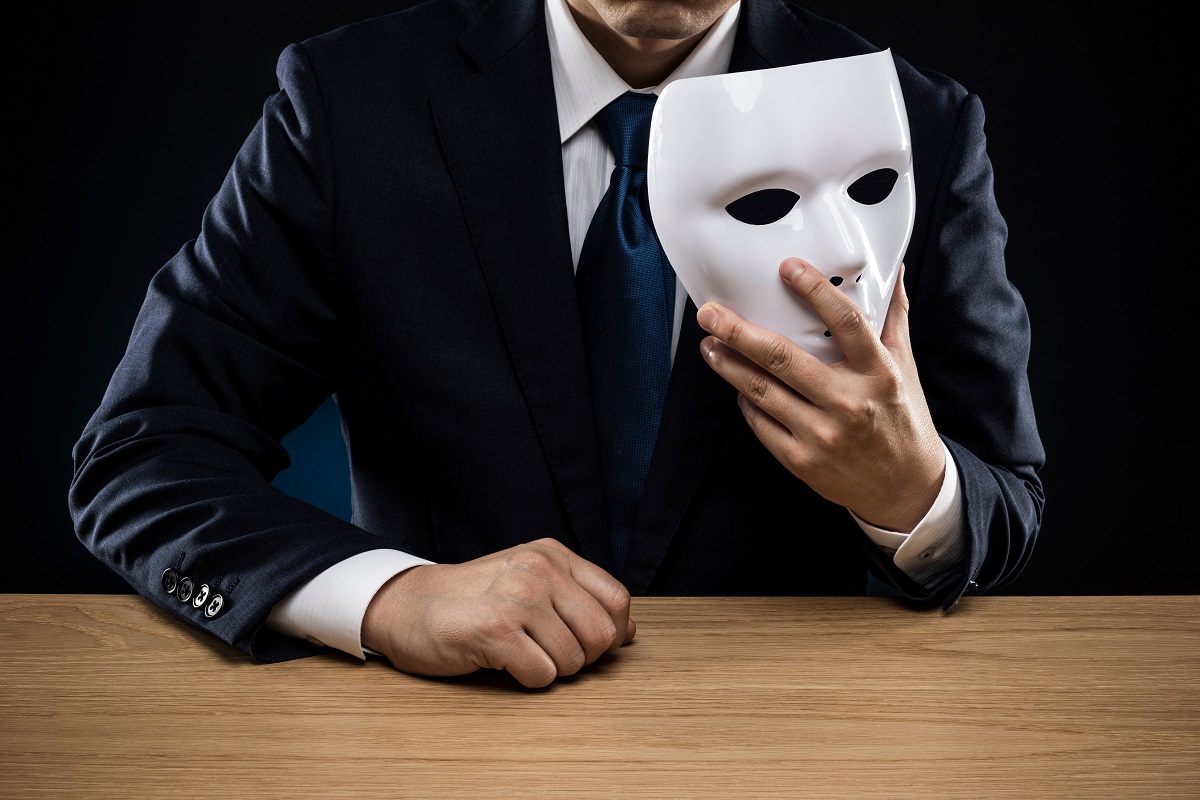 Fraude en entreprise : causes, conséquences et prévention Homme en costume cravate avec un masque pour cacher son identité