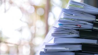 Documents d'affaires non classés sur un bureau avec stylo et trombones, concept de planification budgétaire.